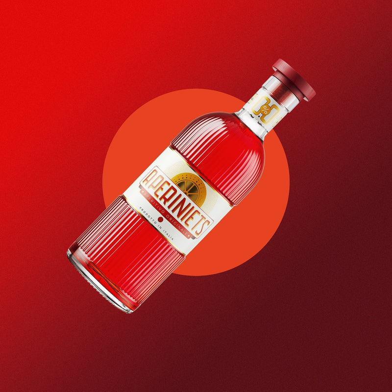Red bottle of Aperiniets, the alcohol-free aperitif drink, on a vibrant background.