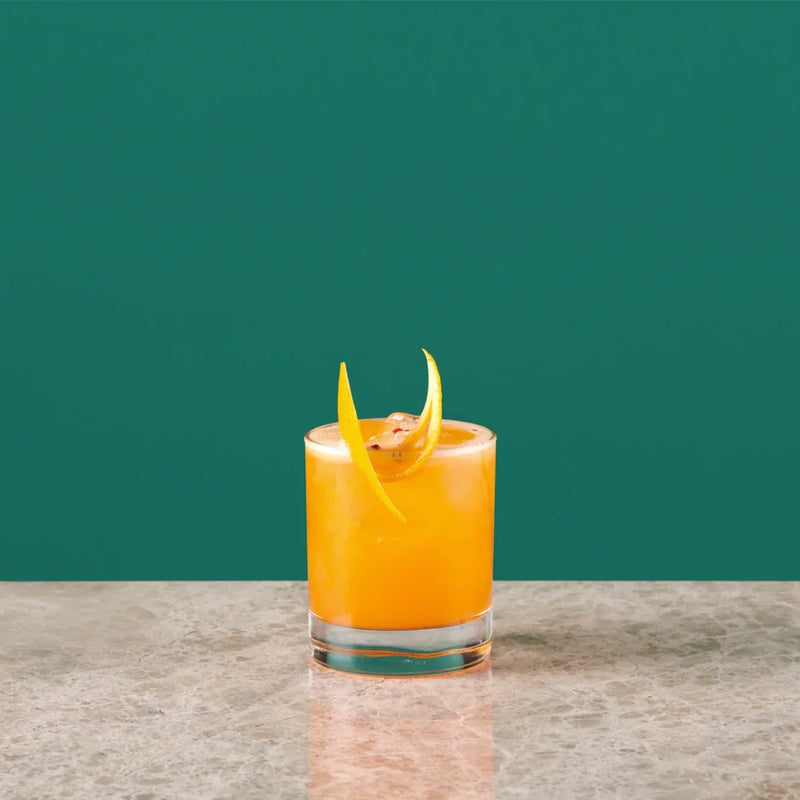 Sling cocktail served in a whisky glass, featuring orange juice and Angostura Bitter, garnished with orange peel.